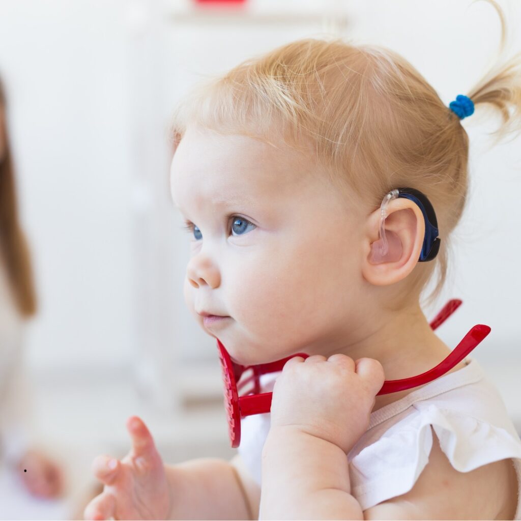 Criança usando aparelho auditivo, sorrindo e interagindo com amigos.